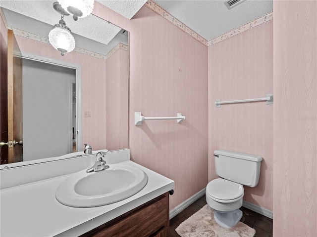 bathroom featuring baseboards, a textured ceiling, toilet, and vanity