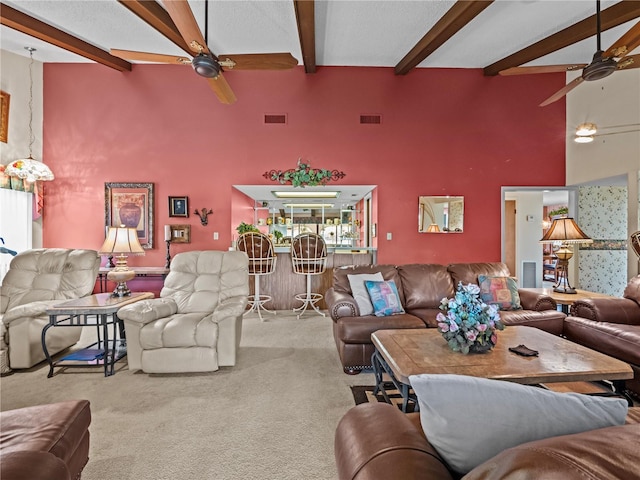 carpeted living area with visible vents, ceiling fan, and beamed ceiling