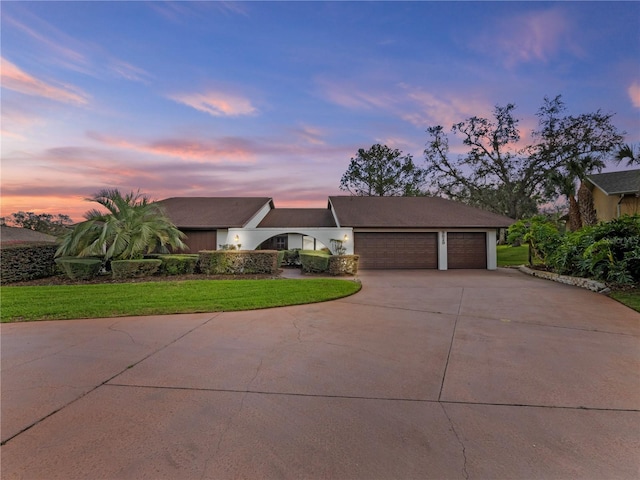 view of front of house with concrete driveway, a lawn, and an attached garage