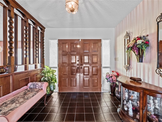 foyer with a textured ceiling and dark tile patterned floors