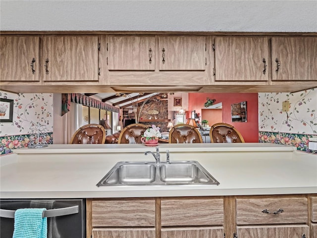 kitchen featuring stainless steel dishwasher, a textured ceiling, light countertops, and a sink