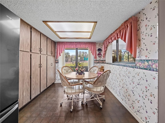 dining area featuring wallpapered walls, baseboards, and a textured ceiling