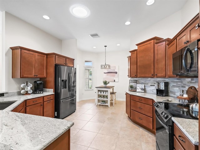 kitchen with light tile patterned floors, light stone counters, decorative light fixtures, black appliances, and backsplash