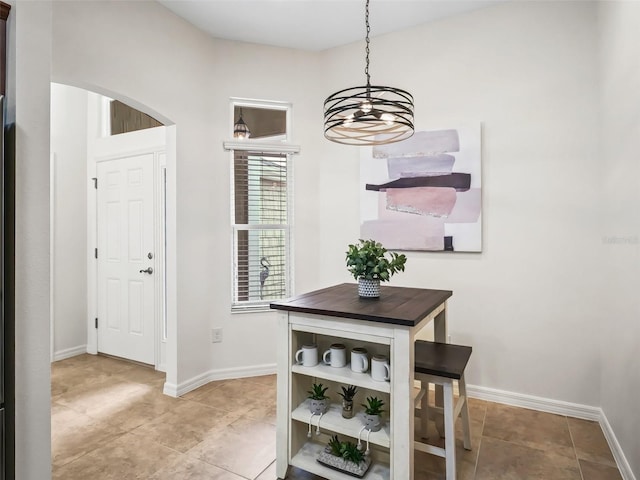 dining area featuring arched walkways, light tile patterned flooring, and baseboards