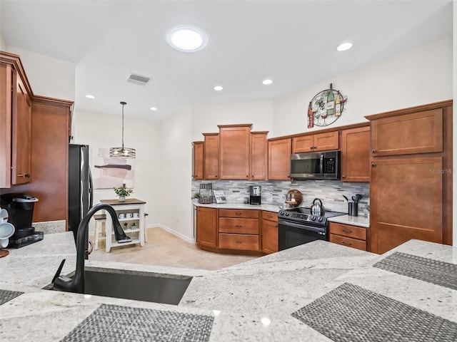 kitchen with electric stove, stainless steel microwave, visible vents, freestanding refrigerator, and a sink