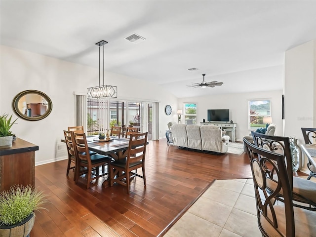 dining area with lofted ceiling, visible vents, wood finished floors, baseboards, and ceiling fan with notable chandelier