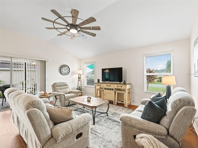 living room with a ceiling fan, vaulted ceiling, baseboards, and wood finished floors