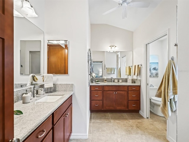 bathroom featuring ceiling fan, two vanities, vaulted ceiling, and a sink