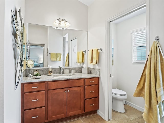 bathroom featuring baseboards, vanity, toilet, and tile patterned floors