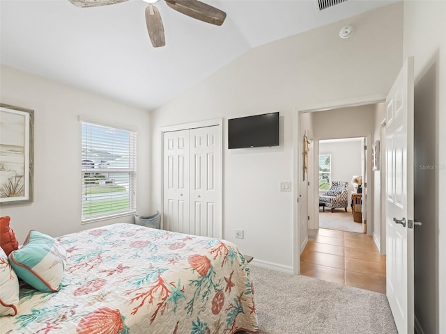 bedroom with light carpet, light tile patterned floors, a ceiling fan, lofted ceiling, and a closet