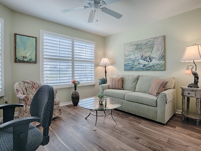 living area featuring ceiling fan, baseboards, and wood finished floors