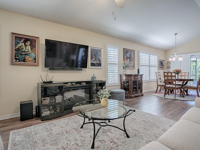 living room with lofted ceiling, a glass covered fireplace, baseboards, and wood finished floors