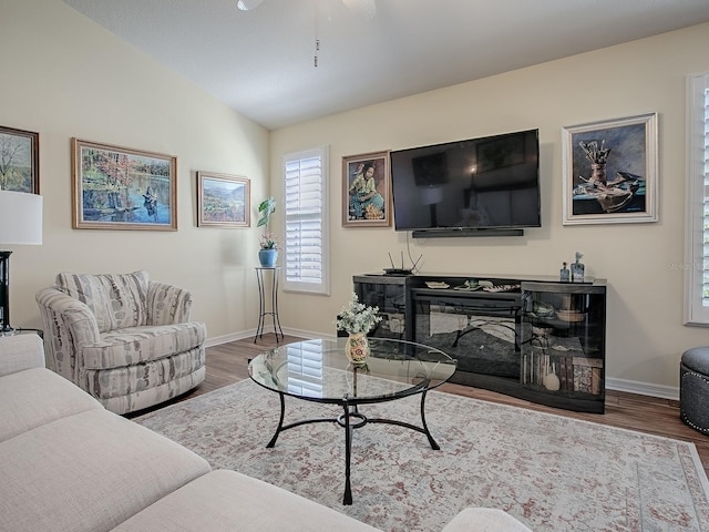 living area featuring vaulted ceiling, wood finished floors, and baseboards