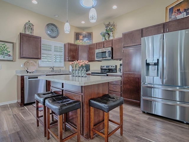 kitchen featuring stainless steel appliances, light wood-style floors, a kitchen breakfast bar, light countertops, and a center island