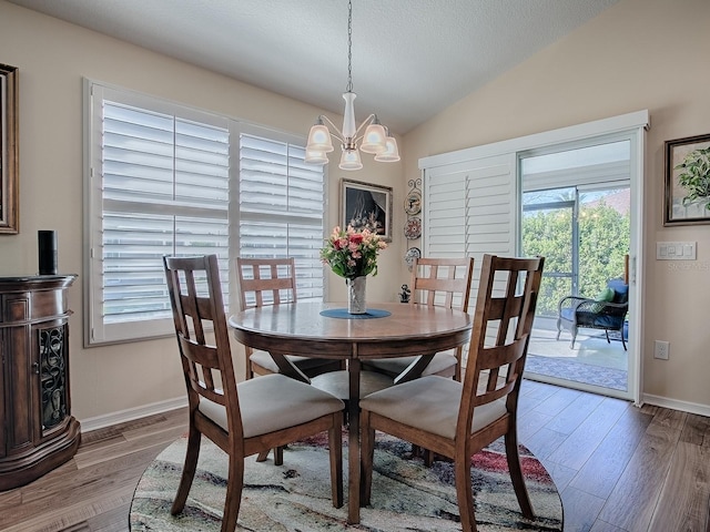 dining room featuring a notable chandelier, vaulted ceiling, baseboards, and wood finished floors