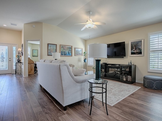 living room with a ceiling fan, visible vents, vaulted ceiling, and wood finished floors