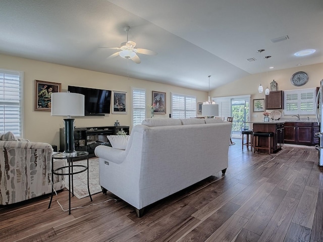 living area featuring ceiling fan, visible vents, vaulted ceiling, and dark wood-style flooring