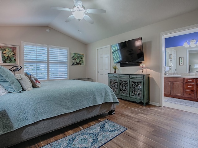 bedroom with light wood-style flooring, ensuite bathroom, vaulted ceiling, a sink, and ceiling fan