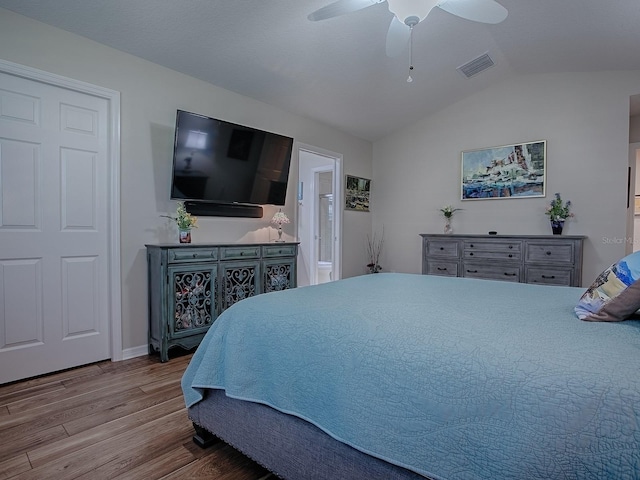 bedroom featuring visible vents, ceiling fan, connected bathroom, vaulted ceiling, and wood finished floors