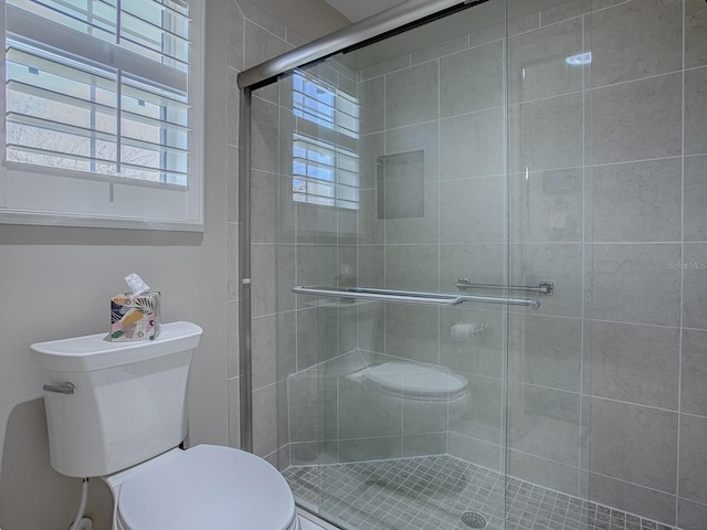 full bath with a wealth of natural light, a shower stall, and toilet