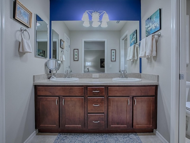 full bathroom with toilet, double vanity, baseboards, and a sink