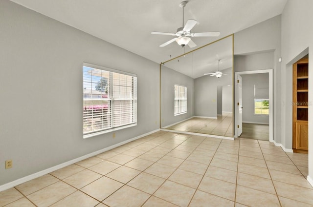 empty room featuring light tile patterned floors, ceiling fan, baseboards, and vaulted ceiling