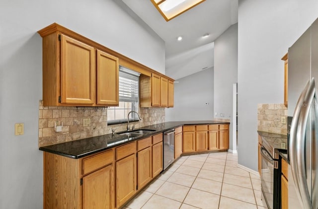 kitchen with light tile patterned floors, dark stone counters, appliances with stainless steel finishes, a sink, and backsplash