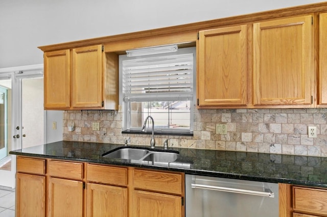 kitchen featuring dishwasher, dark stone countertops, a sink, tile patterned flooring, and backsplash