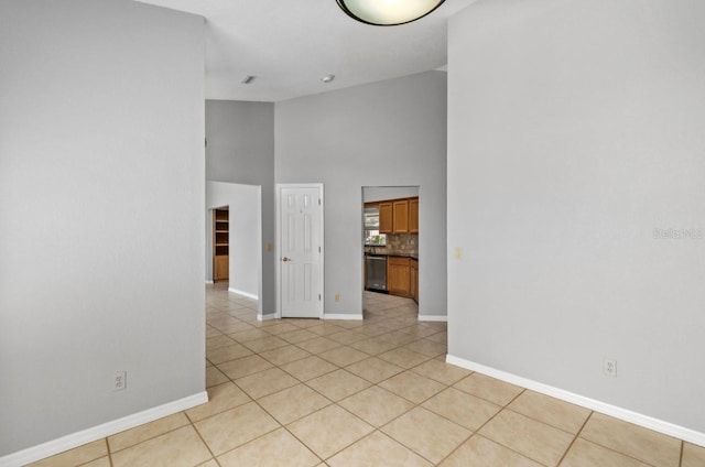 unfurnished room featuring a high ceiling, light tile patterned flooring, and baseboards