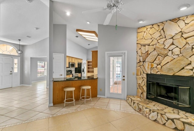 kitchen with light tile patterned floors, dark countertops, open floor plan, a peninsula, and stainless steel appliances