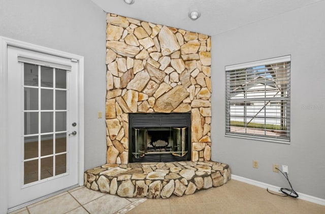 interior details featuring a stone fireplace and baseboards