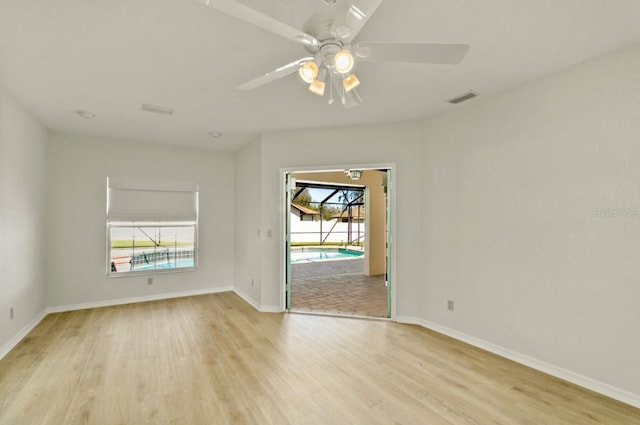 spare room featuring visible vents, baseboards, a sunroom, light wood-style flooring, and ceiling fan