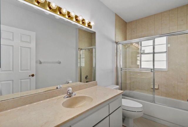 full bathroom featuring bath / shower combo with glass door, tile patterned flooring, vanity, and toilet