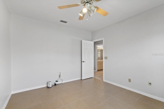 empty room featuring tile patterned flooring, baseboards, visible vents, and a ceiling fan