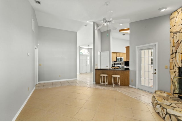 kitchen with ceiling fan, stainless steel appliances, light tile patterned flooring, and high vaulted ceiling