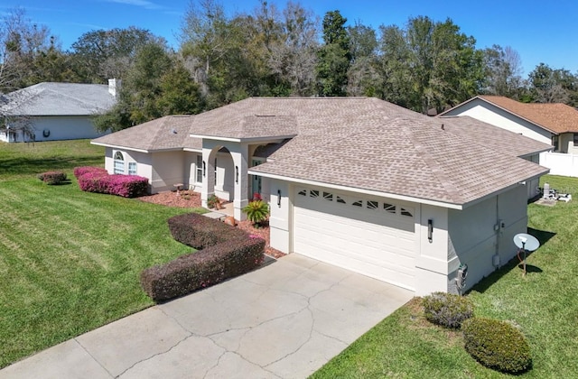 ranch-style home featuring an attached garage, a front lawn, and stucco siding