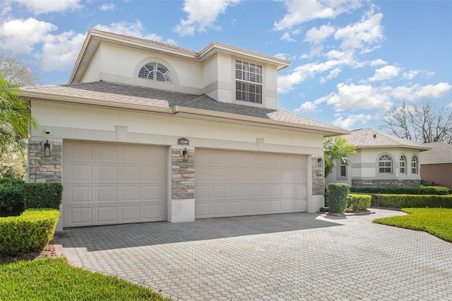 view of front of house featuring stone siding, decorative driveway, and stucco siding