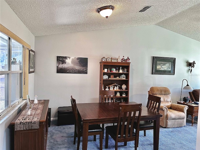 dining space featuring lofted ceiling, carpet flooring, visible vents, and a textured ceiling