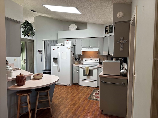 kitchen with white appliances, dark wood-type flooring, vaulted ceiling, gray cabinetry, and under cabinet range hood