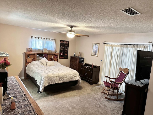 bedroom featuring light carpet, ceiling fan, visible vents, and a textured ceiling