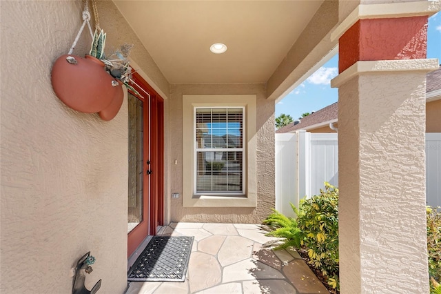 entrance to property with fence and stucco siding