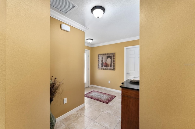 entrance foyer with baseboards, light tile patterned floors, visible vents, and crown molding