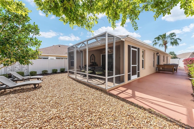 back of house with ceiling fan, glass enclosure, a patio area, and fence