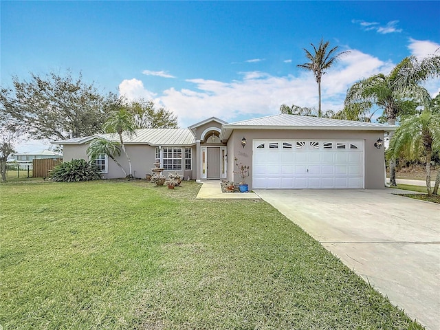 ranch-style house featuring stucco siding, concrete driveway, an attached garage, a front yard, and metal roof