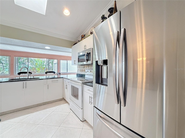 kitchen featuring light tile patterned floors, a sink, appliances with stainless steel finishes, ornamental molding, and tasteful backsplash