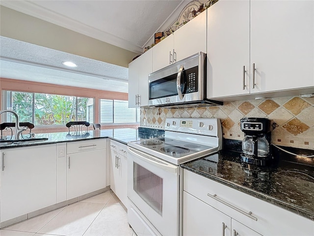 kitchen with light tile patterned flooring, electric range, a sink, decorative backsplash, and stainless steel microwave