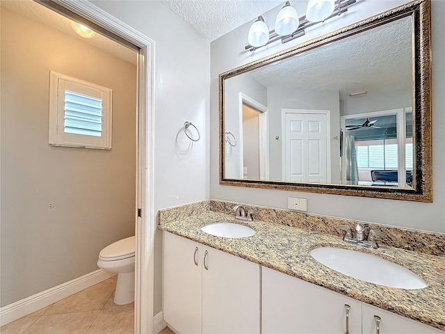 bathroom with a sink, a textured ceiling, toilet, and tile patterned floors