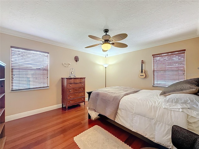 bedroom featuring crown molding, a textured ceiling, baseboards, and wood finished floors