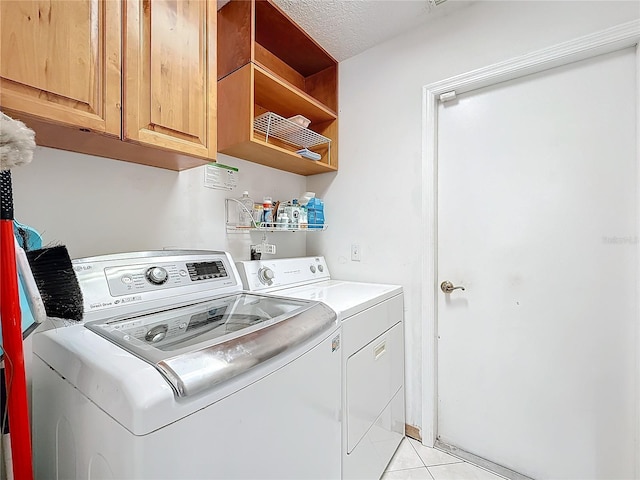 washroom featuring light tile patterned floors, a textured ceiling, washing machine and dryer, and cabinet space