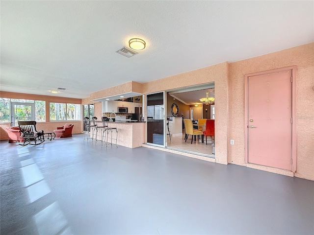 interior space with concrete flooring, visible vents, a textured wall, and an inviting chandelier